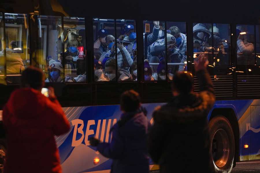 Beijing Olympics Foreign athletes inside a bus respond to residents on a street as they were heading to the National Stadium ahead of the opening ceremony of the 2022 Winter Olympics, in Beijing, Feb. 4, 2022. (AP Photo/Andy Wong)