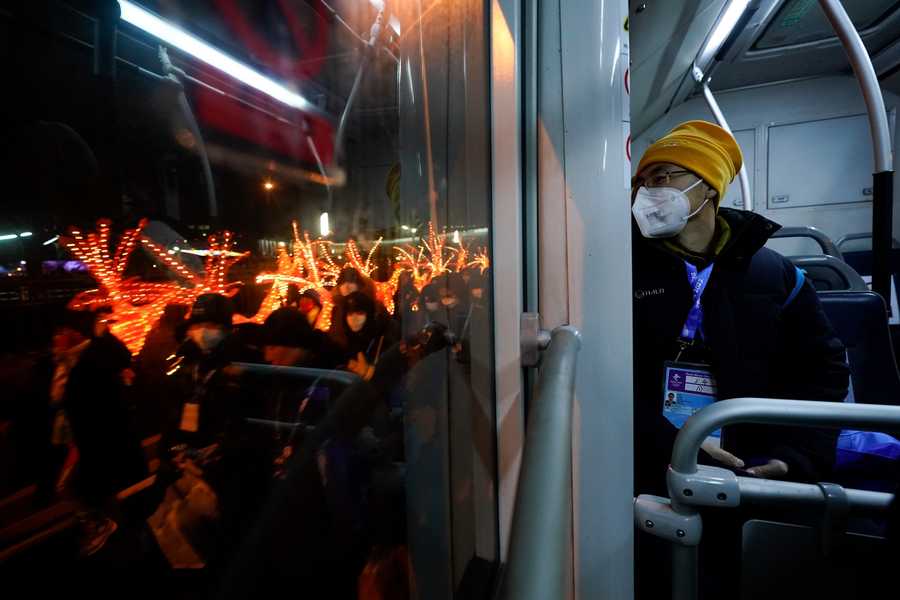 Beijing Olympics Getting A Glimpse Photo Gallery A journalist looks out the window of an Olympic shuttle bus as performers walk along the street with props used at the opening ceremony.